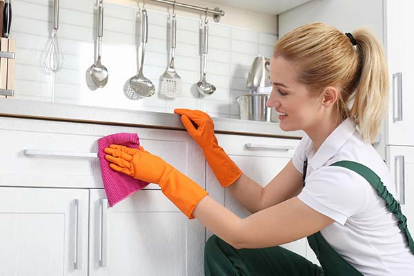 Homeowner cleaning her white kitchen cabinets
