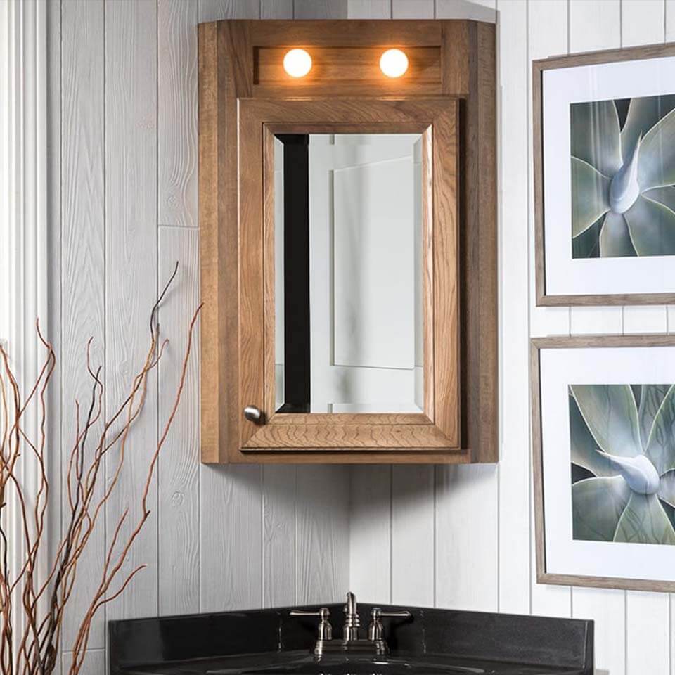 Wooden corner cabinet for over bathroom sink with mirror on door and two accent lights above