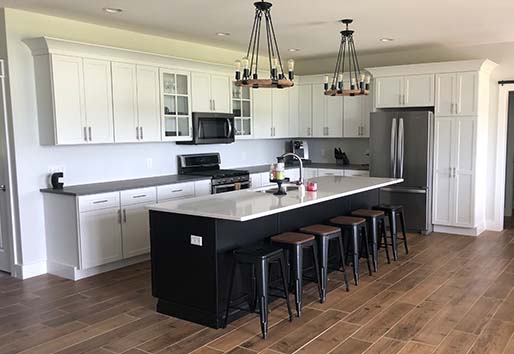 Kitchen with white cabinets and dark island with seating.
