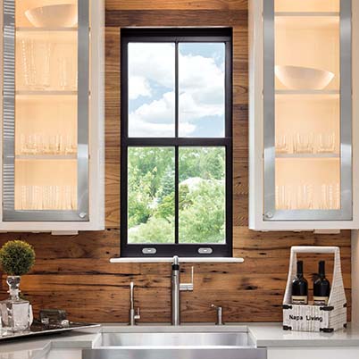 dark single-hung kitchen window over sink between open cabinets with wood backsplash