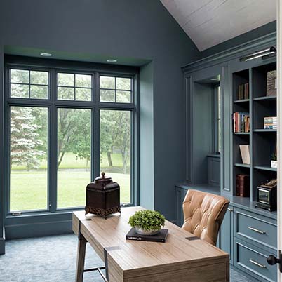 custom office with dark teal walls and built-in bookcases, large matching architectural windows