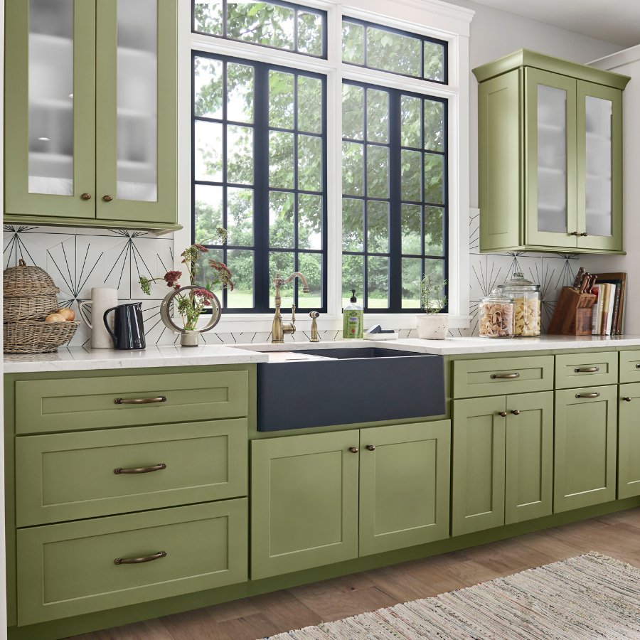 Green kitchen cabinets with black apron sink.