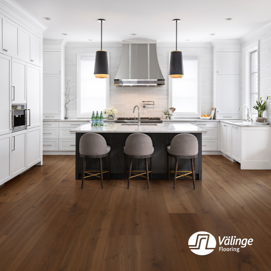 White kitchen with a black island and Valinge flooring
